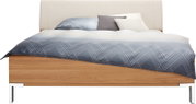 Futonbett mit Holzrahmen und gepolstertem Kopfteil, von vorne gesehen, mit blauer Bettwäsche und mehreren Kissen.