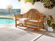 Holzbank mit geschwungener Rückenlehne und Armlehnen, auf einer Terrasse neben einem Pool, umgeben von Pflanzen, aus seitlicher Perspektive fotografiert.