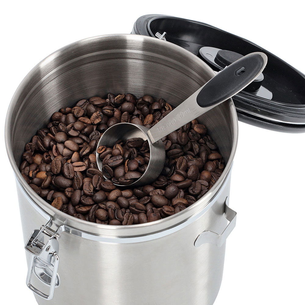 Edelstahl-Kaffeedose mit Löffel, gefüllt mit Kaffeebohnen, aus der Vogelperspektive.