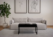 Modernes Couchtisch-Set in schwarzem Design, vor einem hellgrauen Sofa mit minimalistischer Kunst an der Wand, aus der Frontalperspektive.