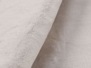 Nahaufnahme eines weißen Fellteppichs mit weicher, flauschiger Textur, seitliche Perspektive