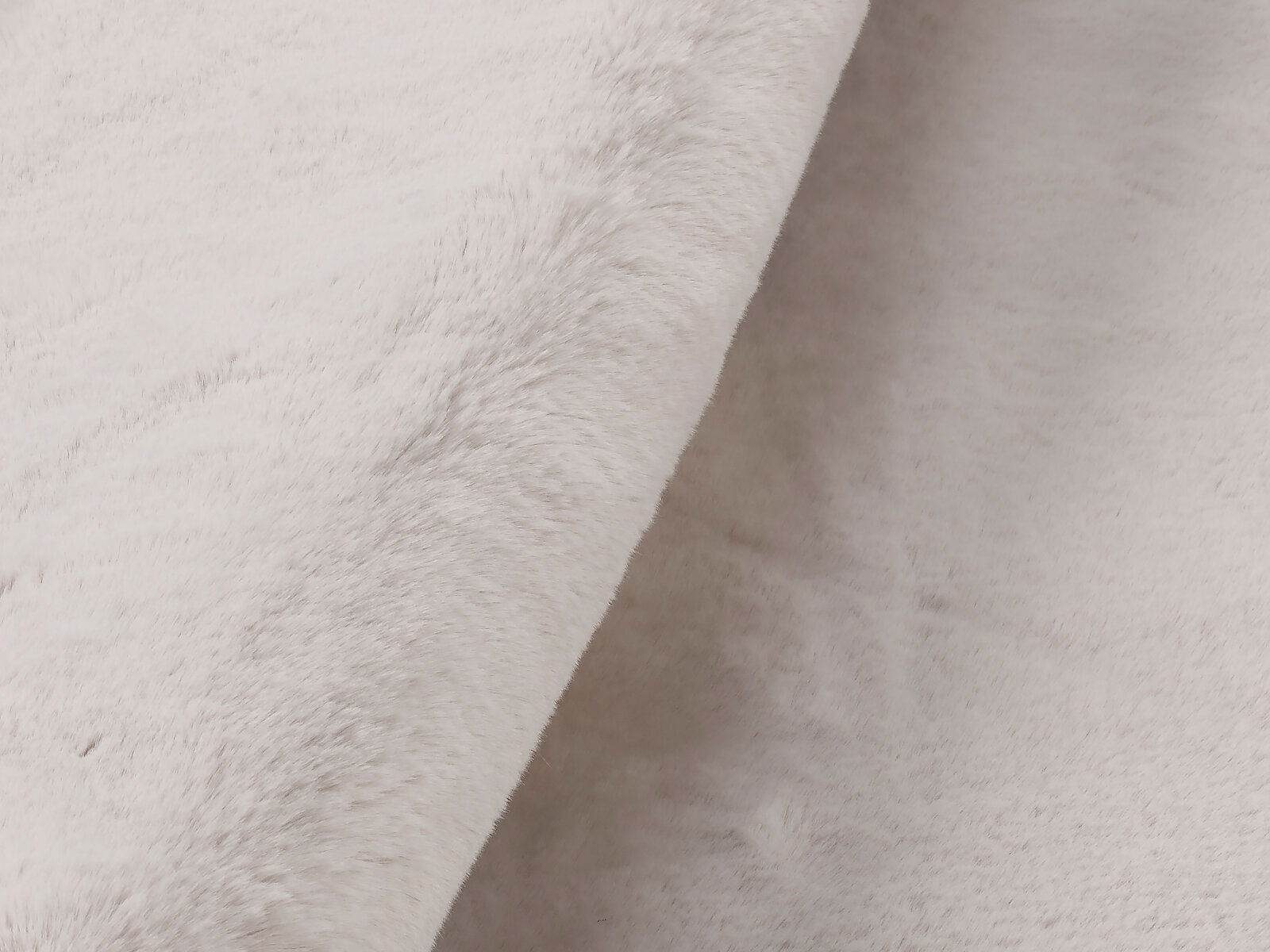 Nahaufnahme eines weißen Fellteppichs mit weicher, flauschiger Textur, seitliche Perspektive