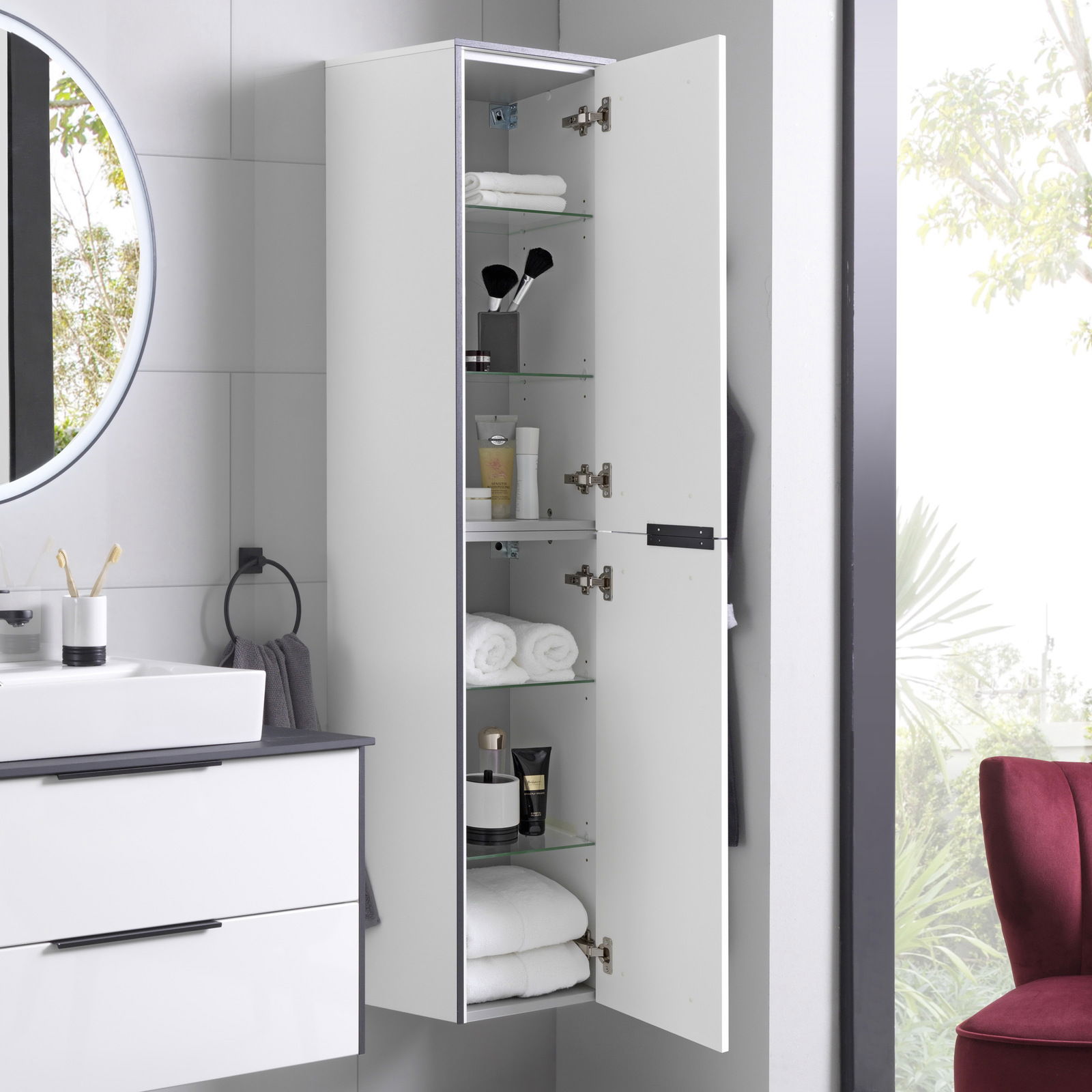 Hochschrank mit geöffneter Tür, gefüllt mit Handtüchern und Pflegeprodukten, seitliche Perspektive