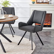 Dunkelgrauer, gepolsterter Polsterstuhl mit Armlehnen und schwarzen Metallbeinen am Esstisch im Wohnzimmer, seitliche Frontansicht (3/4-Perspektive)