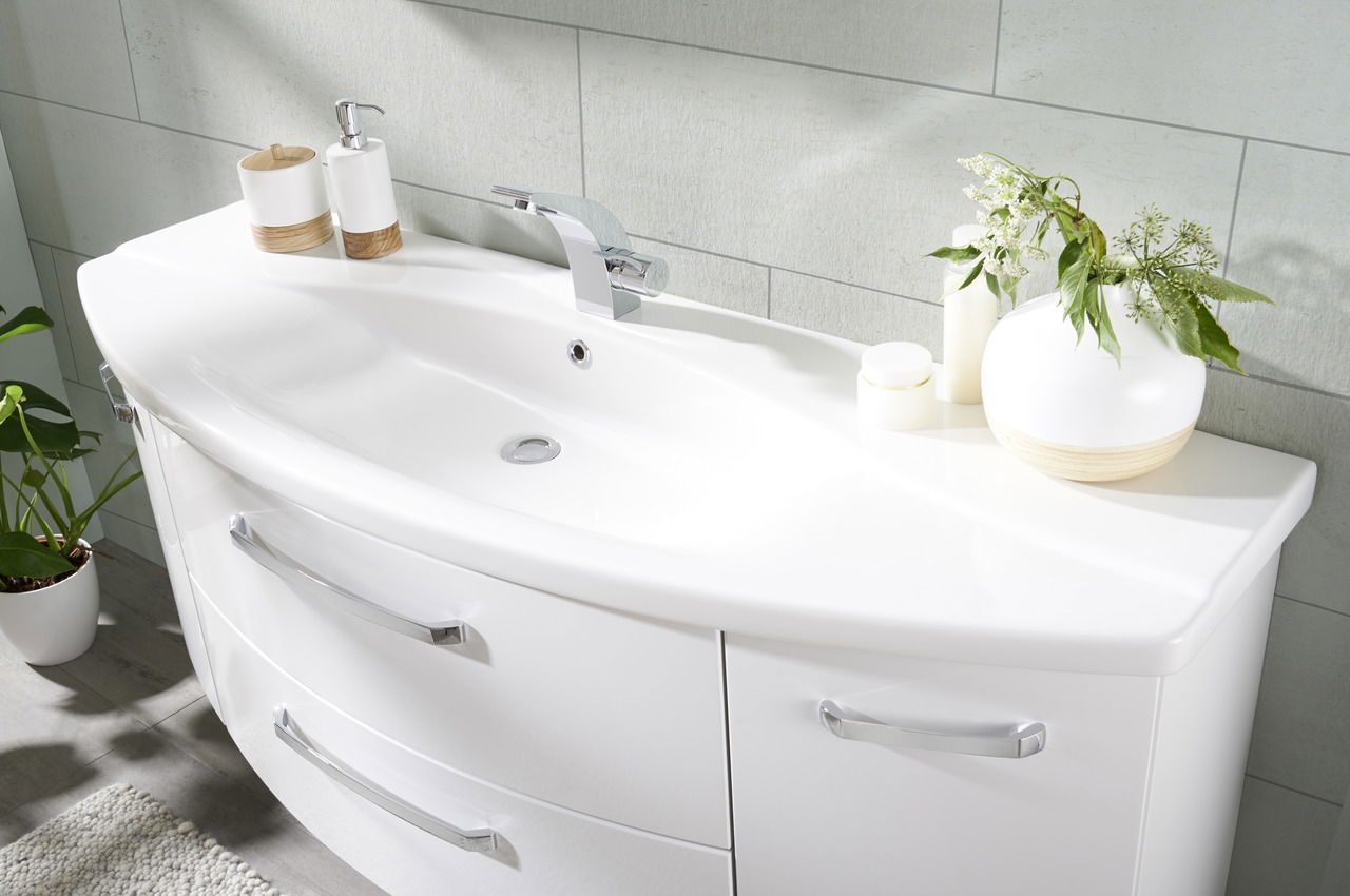 Moderne Badkombination mit weißem Waschbecken und Unterschrank, dekoriert mit Pflanzen und Accessoires, aus seitlicher Perspektive fotografiert.