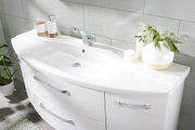 Moderne Badkombination mit weißem Waschbecken und Unterschrank, dekoriert mit Pflanzen und Accessoires, aus seitlicher Perspektive fotografiert.