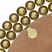 Nahaufnahme eines runden Spiegels mit einem dekorativen Rahmen aus goldenen Kugeln, von der Rückseite betrachtet.