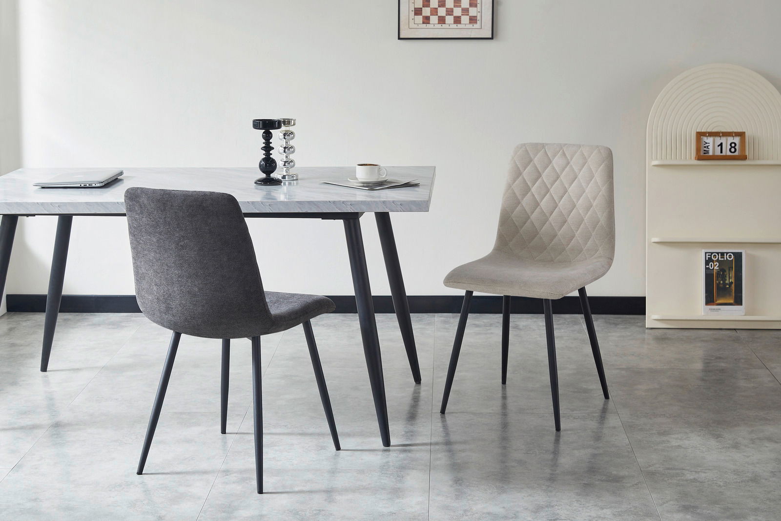 Zwei moderne Stühle in einem Esszimmer, einer in Grau und der andere in Beige, vor einem Tisch mit Marmoreffekt. Perspektive von vorne.