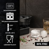 Eiswürfelform aus Silikon, geeignet für Backofen und Spülmaschine, mit zwei Eiswürfeln und einem Glas auf einer Küchenarbeitsplatte, seitliche Perspektive.
