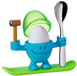 Blauer Eierbecher McEgg mit einem Ei, einem Löffel und einem Hammer, auf einem grünen Sockel stehend, frontal betrachtet.