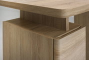 Nahaufnahme eines Schreibtisches aus Holz mit abgerundeten Kanten, seitliche Perspektive