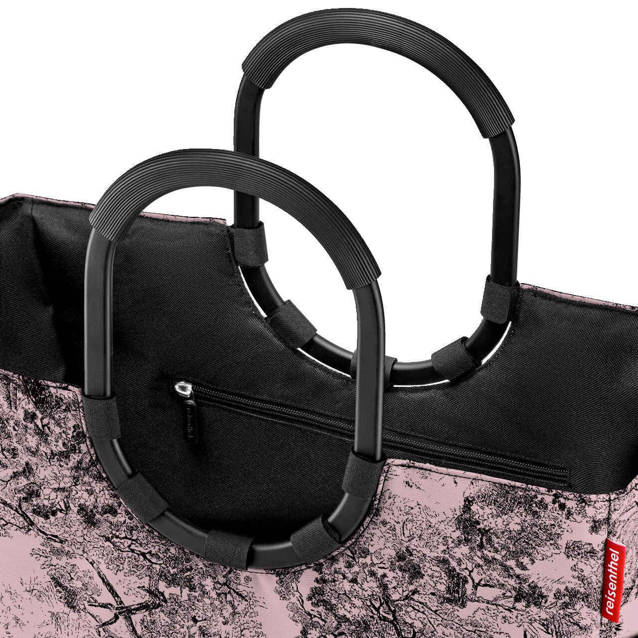 Nahaufnahme einer stilvollen Einkaufstasche mit schwarzen, ovalen Griffen und einem rosa-weißen Baum-Muster. Die Tasche hat einen Reißverschluss und das Bild zeigt die obere Perspektive.