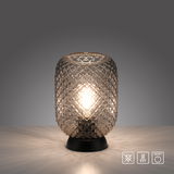 Elegante Tischleuchte mit strukturiertem Glasdesign, frontal auf einem Tisch platziert, mit warmem Lichtschein.