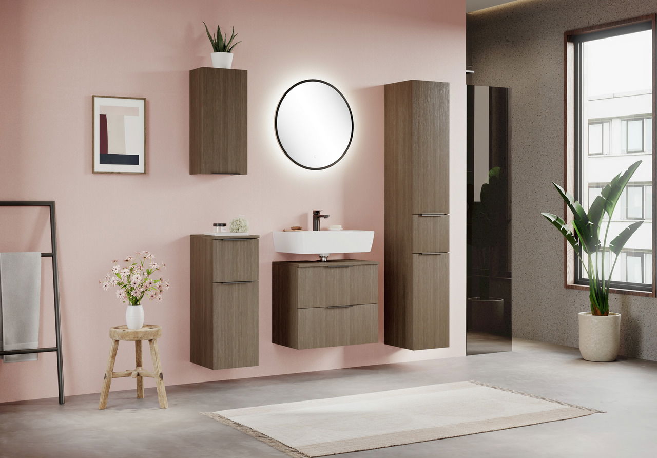 Moderner Waschbeckenunterschrank in Holzoptik, frontal betrachtet, in einem stilvoll eingerichteten Badezimmer mit rosa Wand und runden Spiegel.