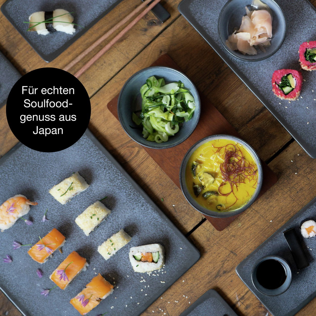 Vogelperspektive auf ein 29-teiliges Sushi-Set mit blauen Tellern, präsentiert mit verschiedenen Sushi-Varianten, Sojasauce und Beilagen auf einem Holztisch.