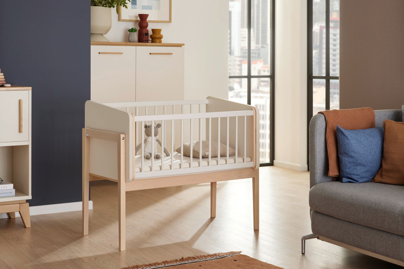 Paidi Anstellbett LITTLE CLOUD Anstellbett aus Holz mit weißen Gitterstäben in einem modernen Wohnzimmer, seitliche Perspektive
