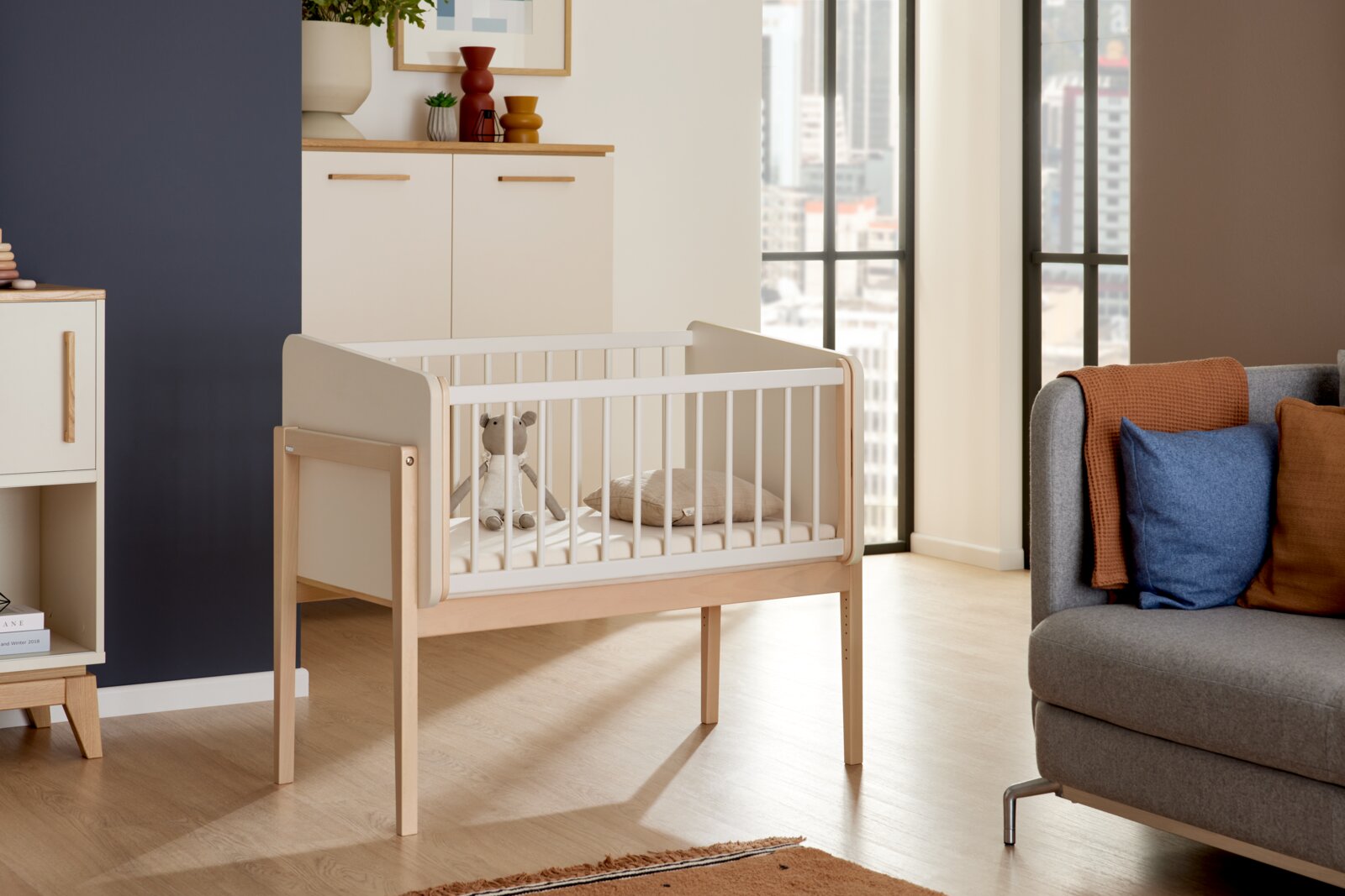 Houten opstapbed met witte spijlen in een moderne woonkamer, zijaanzicht