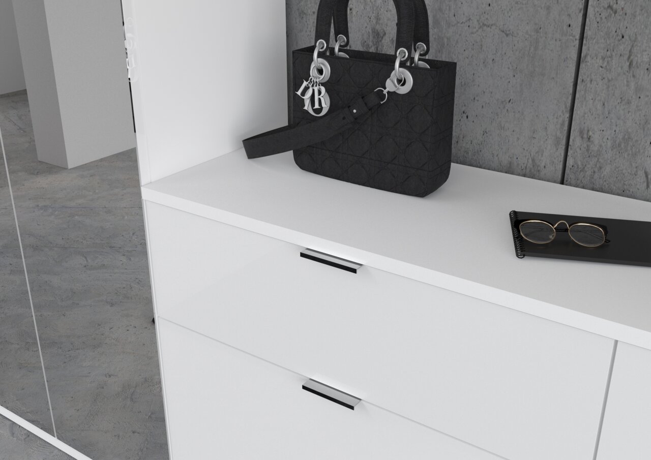 Weiße Kommode mit zwei Schubladen, darauf eine schwarze Handtasche und eine Brille, seitliche Perspektive