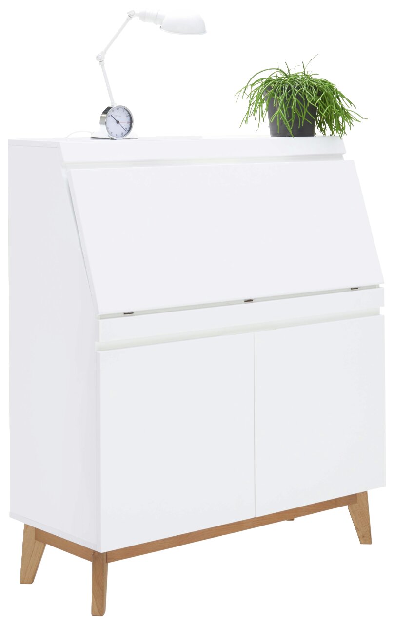 Weißer Sekretär mit schräger Frontansicht, darauf eine Tischlampe, ein Wecker und eine grüne Pflanze.