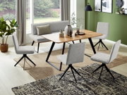Eetkamer met een moderne inrichting, bestaande uit een houten tafel, een grijze bank en vier bijpassende stoelen. Het perspectief toont de ruimte vanuit een schuine bovenhoek, met uitzicht op de tafelset en de groene muur op de achtergrond.