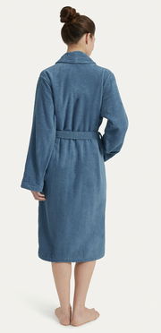 Rückansicht eines blauen Bademantels mit Schalkragen, getragen von einer Person. Der Bademantel hat einen Gürtel und lange Ärmel.