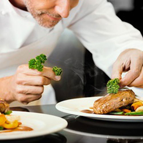 Ein Koch, der zwei Teller anrichtet.