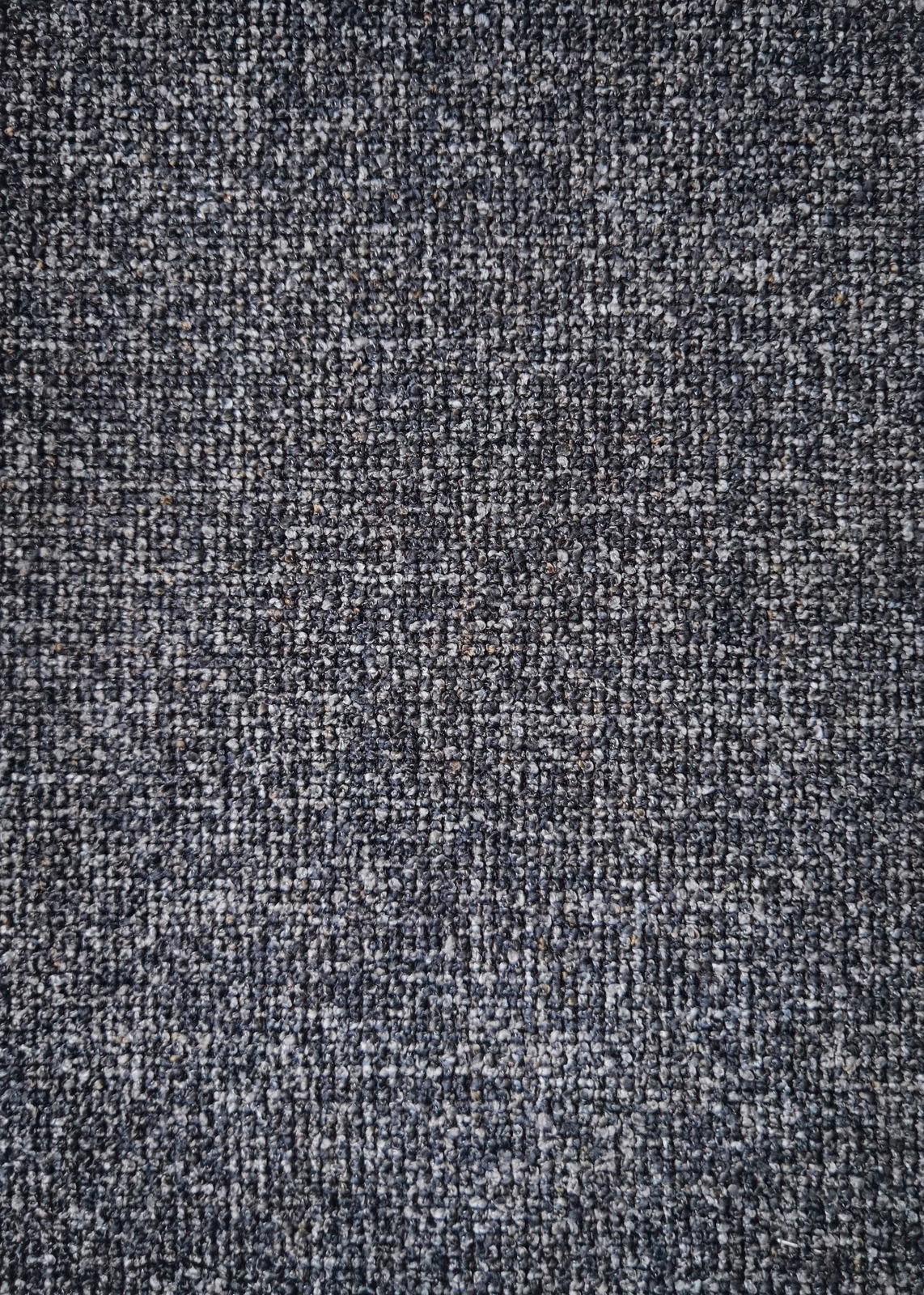 Nahaufnahme eines grauen Stoffmusters, das für einen Armlehnstuhl verwendet wird, von oben betrachtet.