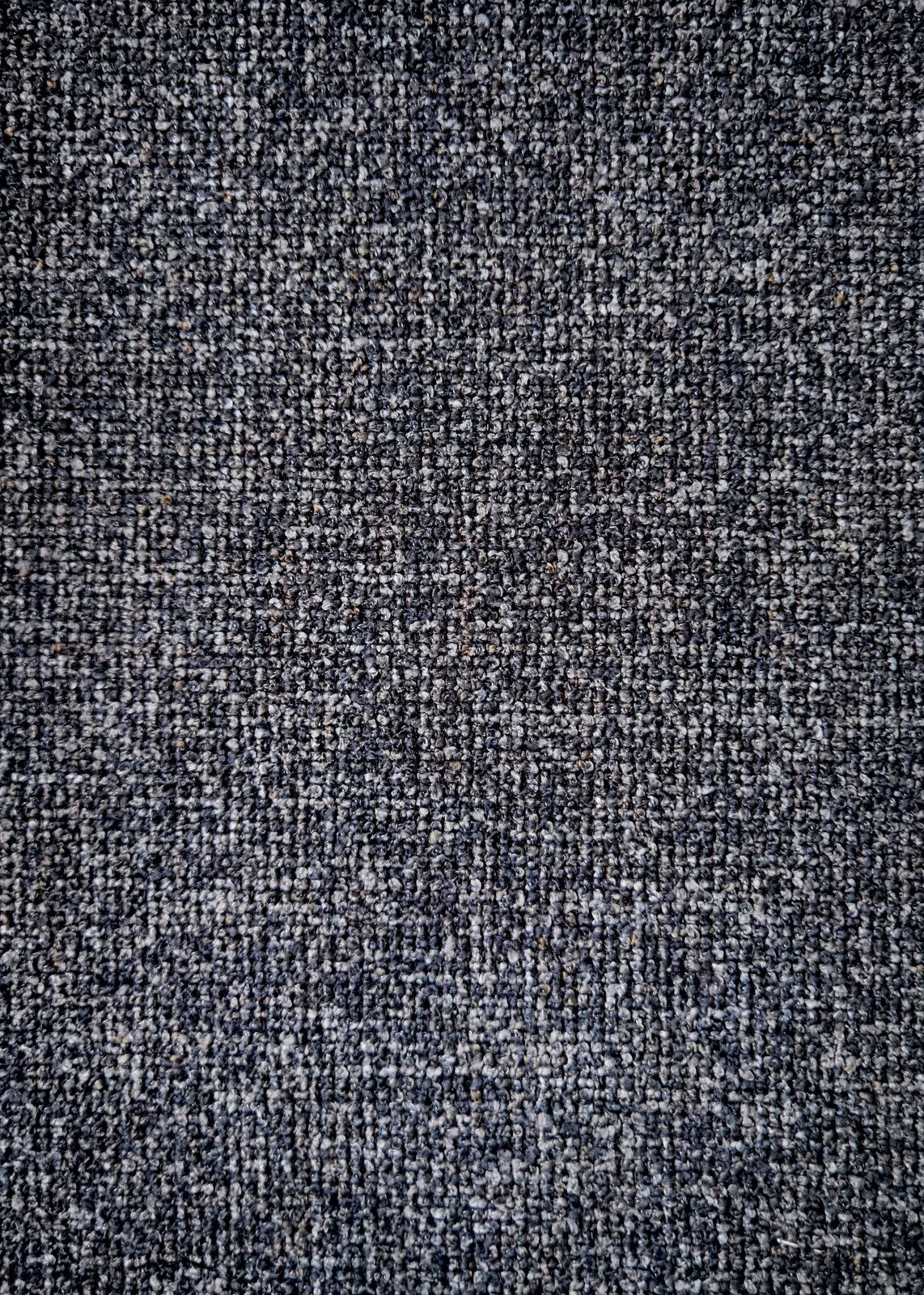 Dieter Knoll Armlehnstuhl PABLO Nahaufnahme eines grauen Stoffmusters, das für einen Armlehnstuhl verwendet wird, von oben betrachtet.