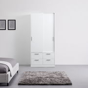 Weißer Schiebetürenschrank mit zwei Türen und vier Schubladen, frontal fotografiert in einem modernen Schlafzimmer.