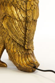 Detailansicht einer goldenen Tischleuchte in Form eines Vogels mit detaillierten Federn und einem Kabel, das aus der Basis herausragt.