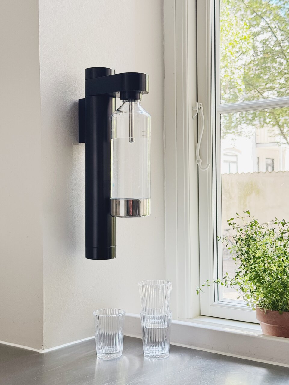 Wandmontierter Wassersprudler in einer modernen Küche, seitliche Perspektive.