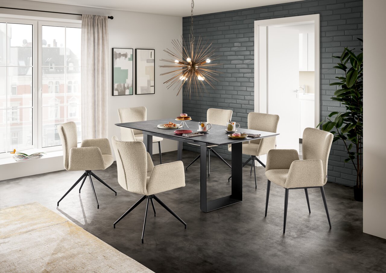 Set one by Musterring Armlehnstuhl SET ONE EL PASO Esszimmer mit sechs beigen Armlehnstühlen um einen rechteckigen Tisch, moderne Hängelampe und große Fenster im Hintergrund, seitliche Perspektive.