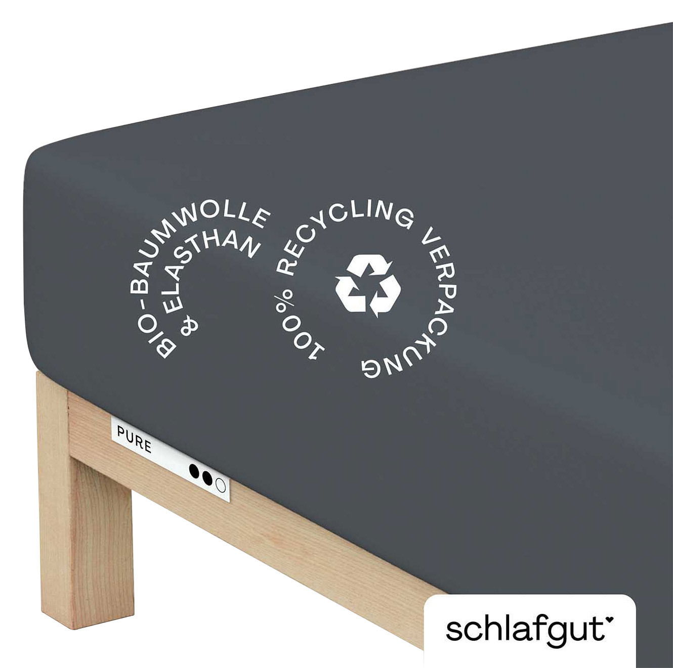 schlafgut Spannbettlaken XL 556 Pure Dunkelgraues Spannbettlaken aus Bio-Baumwolle und Elasthan, auf einer Matratze mit Holzrahmen, seitliche Perspektive