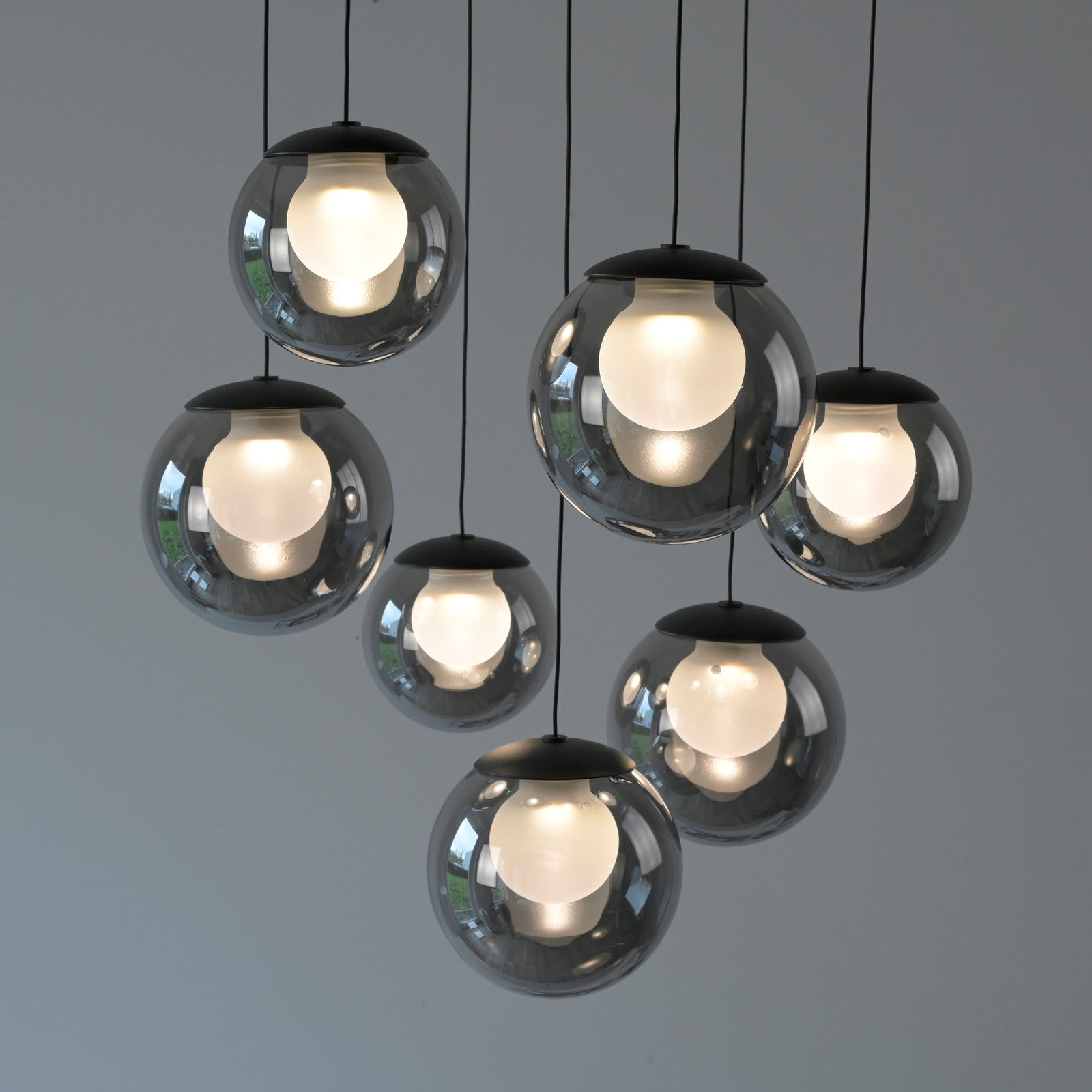 Moderne LED-Pendelleuchte mit sieben kugelförmigen, rauchgrauen Glaskörpern, von unten betrachtet.