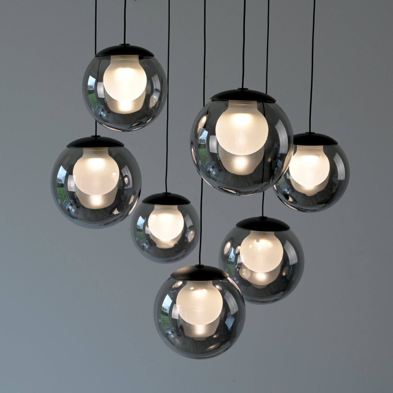 Moderne LED-Pendelleuchte mit sieben kugelförmigen, rauchgrauen Glaskörpern, von unten betrachtet.