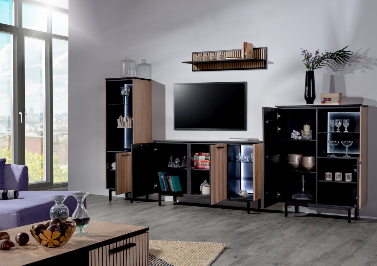 Moderne woonkamermeubels in een lichte ruimte met een tv-kast, wandplank en vitrinekast, gezien vanaf de zijkant.