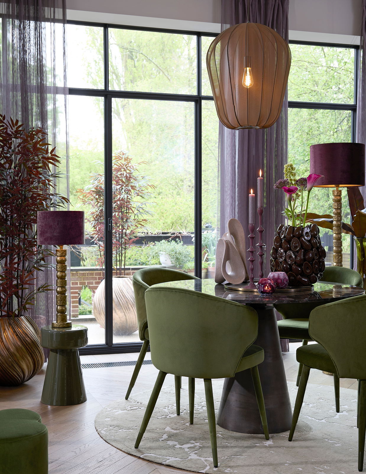 Light&Living Vaas YATUNG Elegante Vase im antiken Stil, platziert auf einem Tisch in einem stilvoll eingerichteten Raum mit grünen Stühlen und großen Fenstern im Hintergrund, seitliche Perspektive.
