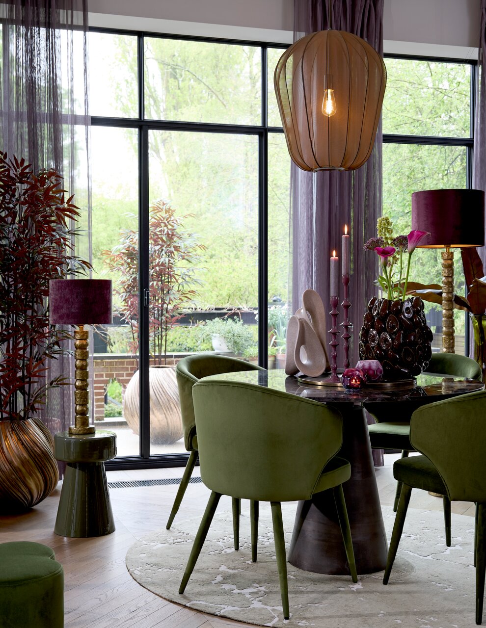 Light&Living Vase YATUNG Elegante Vase im antiken Stil, platziert auf einem Tisch in einem stilvoll eingerichteten Raum mit grünen Stühlen und großen Fenstern im Hintergrund, seitliche Perspektive.