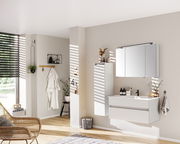 Moderne Badezimmermöbel in heller, minimalistischer Einrichtung, mit einem hängenden Waschtisch und Spiegelschrank, seitliche Perspektive.