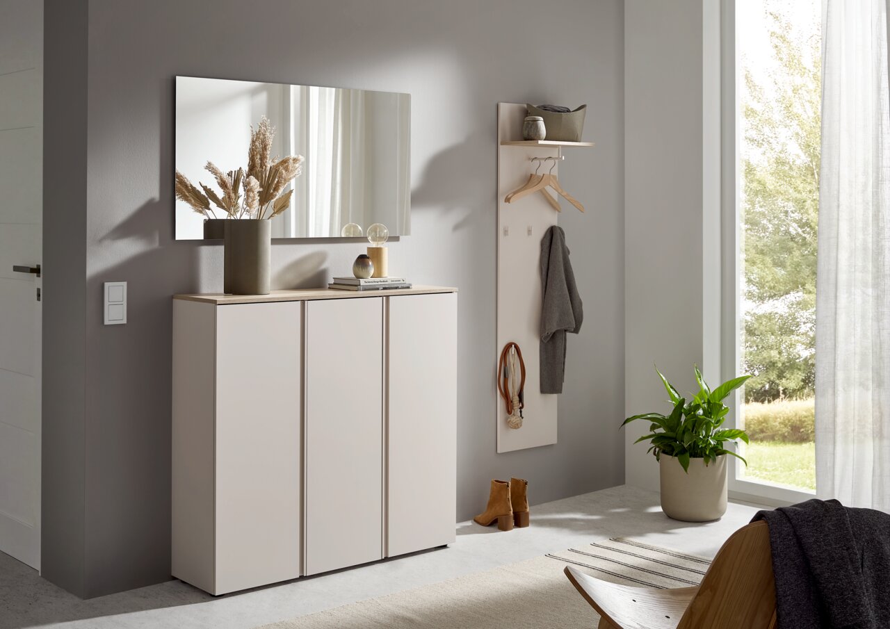 Voleo Garderobenpaneel lang MILTON Modernes Flurmöbel-Set mit weißem Schuhschrank mit Holzoptik-Abdeckplatte und Wandspiegel sowie Garderobenpaneel mit Ablage und Haken, frontal in leicht schräger Perspektive im hellen Eingangsbereich