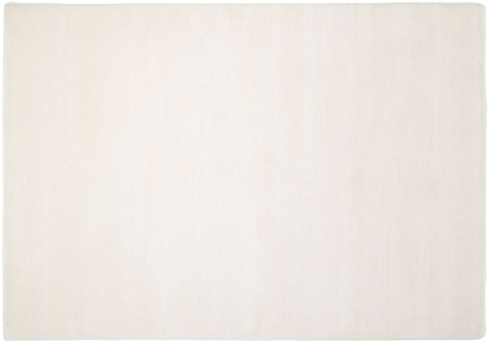 Einfacher, rechteckiger Wollteppich in cremeweißer Farbe, aus der Vogelperspektive fotografiert.