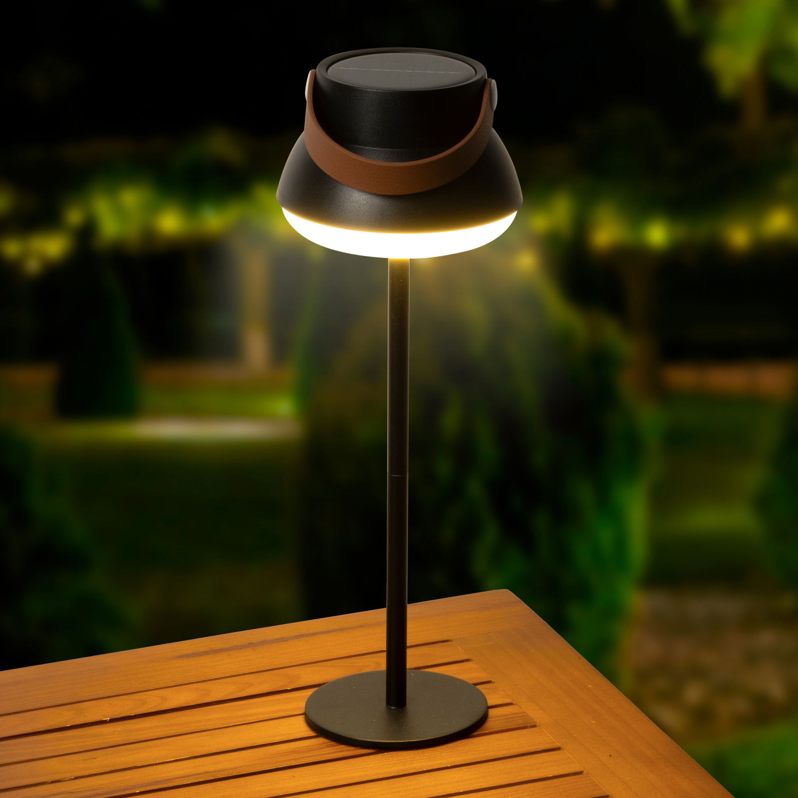 Lumineo Solar Tischlampe Solar Tischlampe auf einem Holztisch, beleuchtet in einer nächtlichen Gartenumgebung, seitliche Perspektive