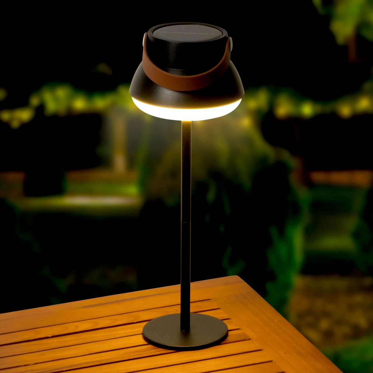 Lumineo Solar Tischlampe Solar Tischlampe auf einem Holztisch, beleuchtet in einer nächtlichen Gartenumgebung, seitliche Perspektive