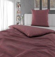 Bordeauxfarbene Bettwäsche mit passendem Kissen auf weißem Bett im modernen Schlafzimmer, Ansicht schräg von vorne/leicht von oben