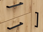 Nahaufnahme einer Kommode aus hellem Holz mit schwarzen Griffen, seitliche Perspektive