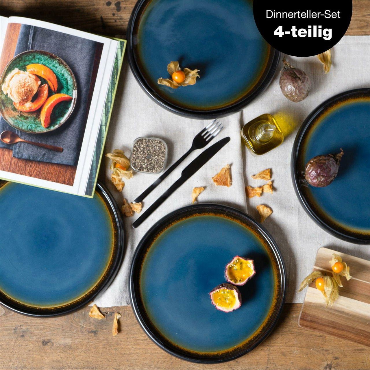 Vogelperspektive auf ein 4-teiliges Dinner-Teller-Set in Blau-Braun, dekoriert mit exotischen Früchten und Gewürzen auf einem Holztisch.