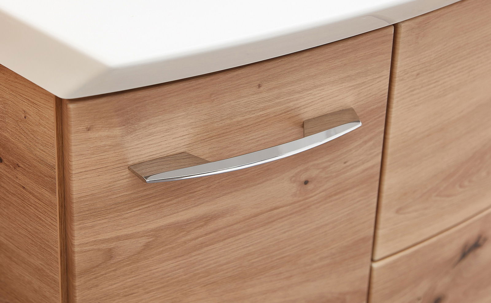 Nahaufnahme eines Badezimmerschranks mit Holzoptik und einem modernen, gebogenen Metallgriff.