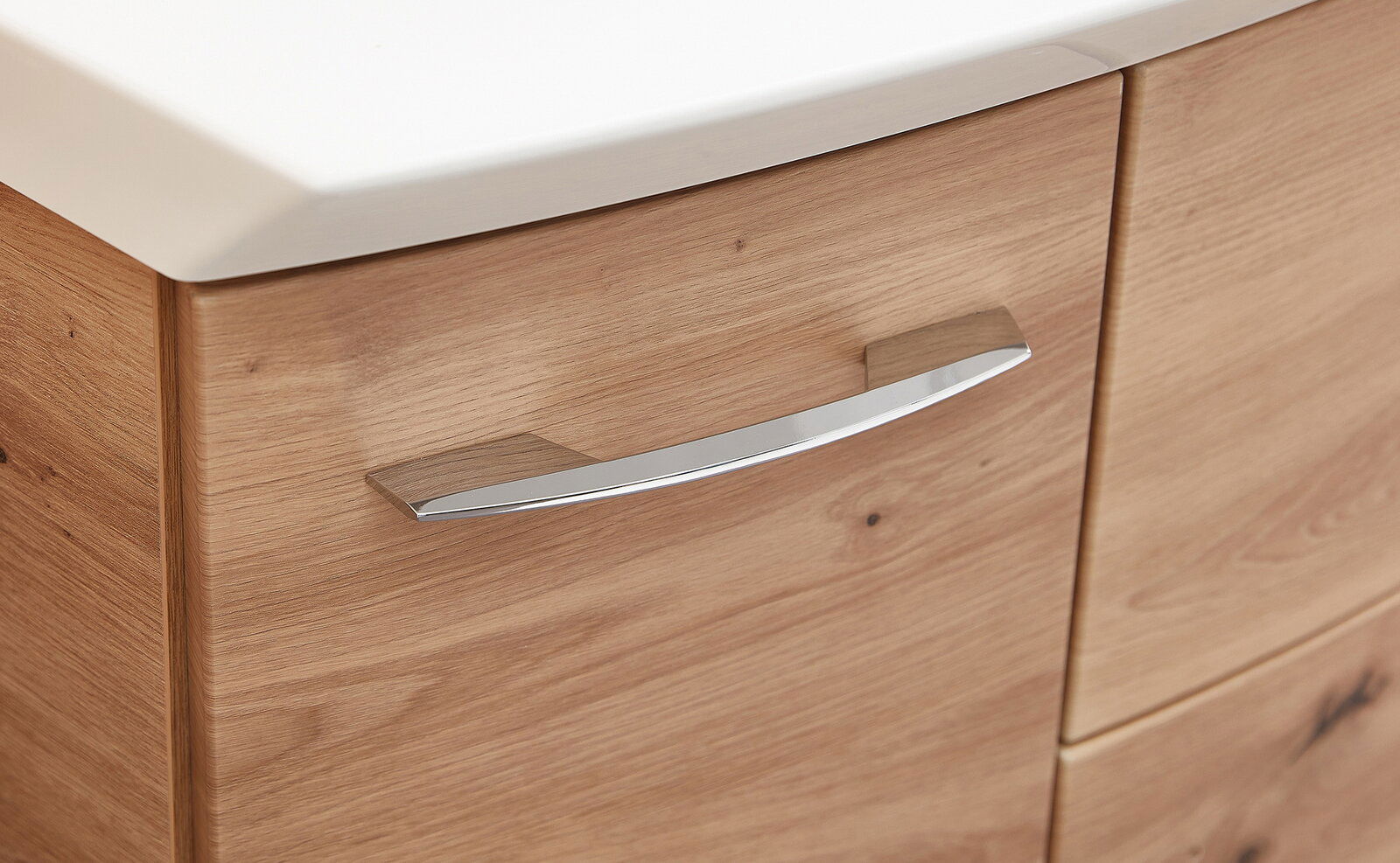 Nahaufnahme eines Badezimmerschranks mit Holzoptik und einem modernen, gebogenen Metallgriff.