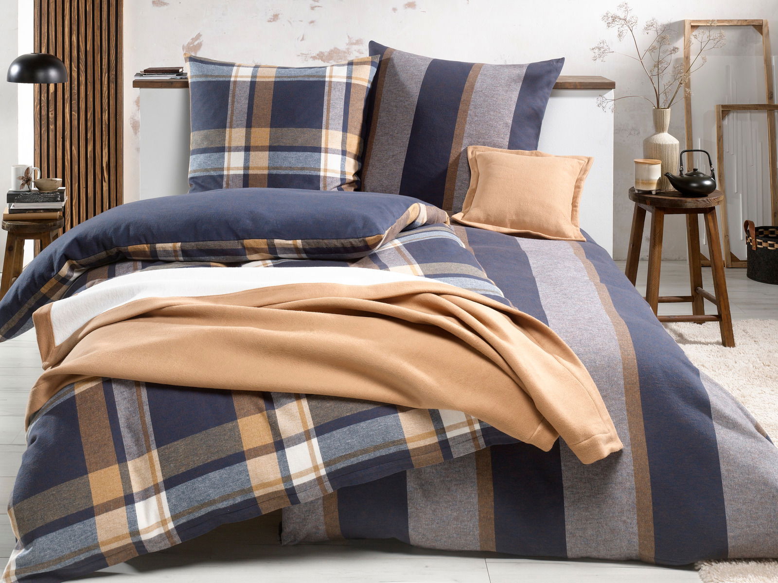 Bett mit Wendebettwäsche in Blau- und Brauntönen, kariertes und gestreiftes Muster, seitliche Perspektive