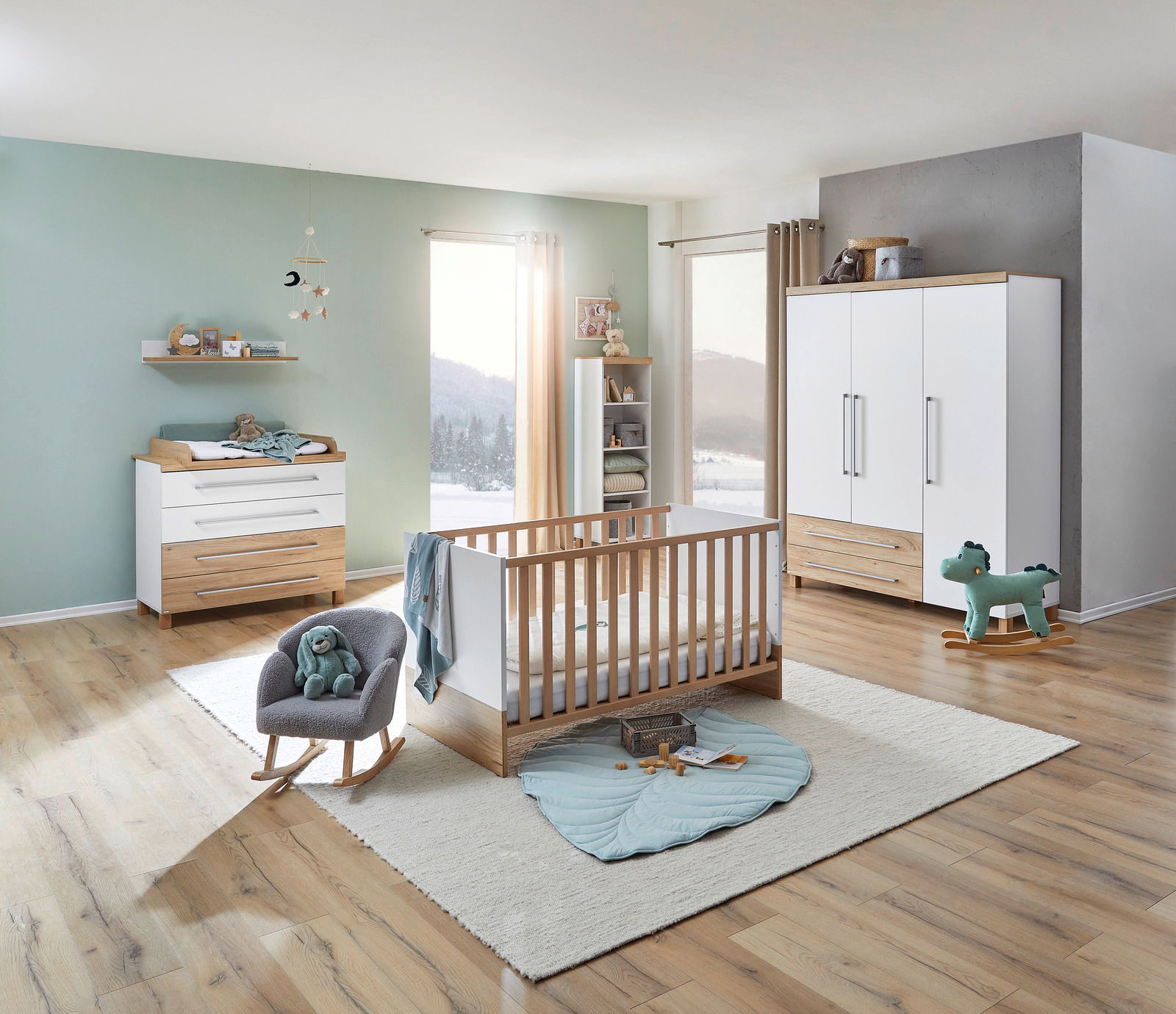 Modernes Babyzimmer mit Wickelkommode, Babybett, Wandregal und dreitürigem Kleiderschrank in Holz- und Weißtönen, seitliche Perspektive